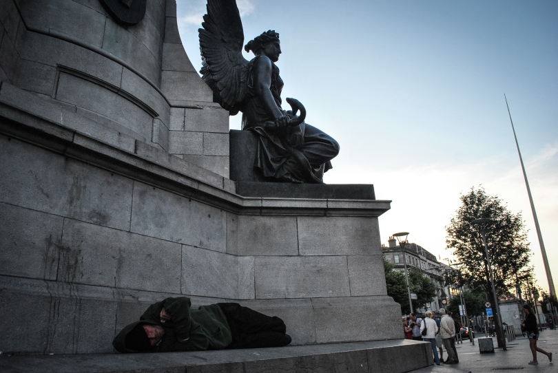 A man sleeps under the angels of Daniel O'Connell's statue at the top of O'Connell street, Dublin's main street.