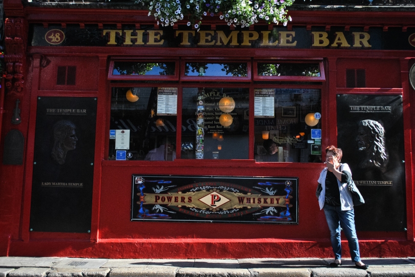 A woman smokes a cigarette outside the famous Temple Bar in the Temple Bar district in central Dublin.